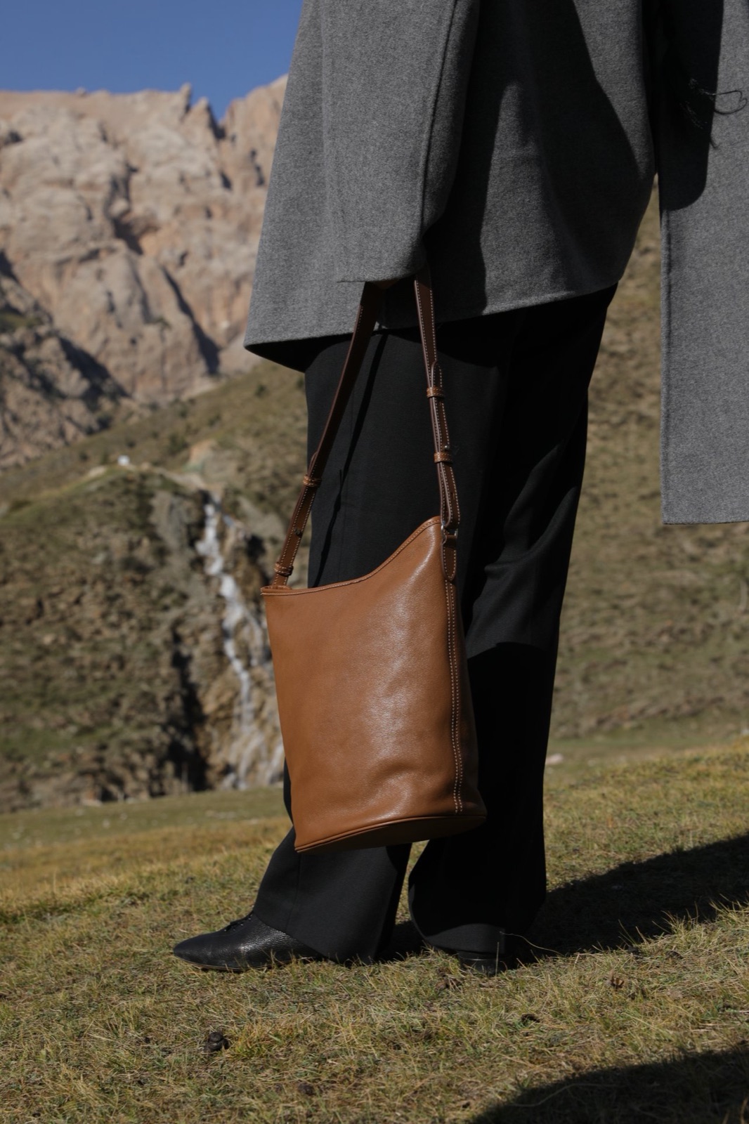 Tan full-grain leather bucket bag worn crossbody